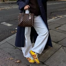 Trainer Colour Trends 2025: @rebeccaferrazwyatt wears yellow trainers with white jeans and a navy coat