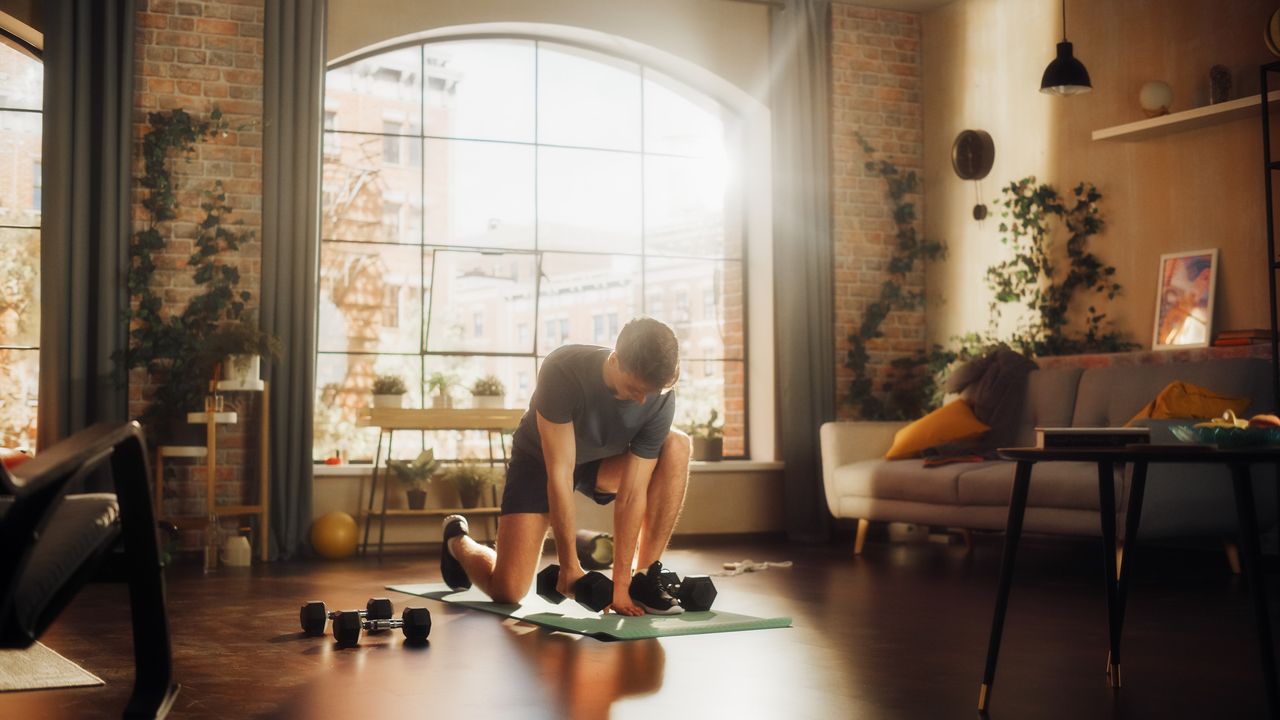 A man preparing for a dumbbell abs workout in his apartment