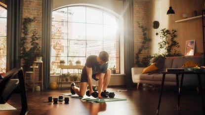 A man preparing for a dumbbell abs workout in his apartment