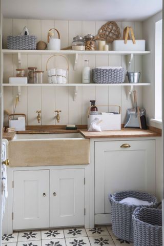 off white laundry room with open shelving butler sink and brass taps