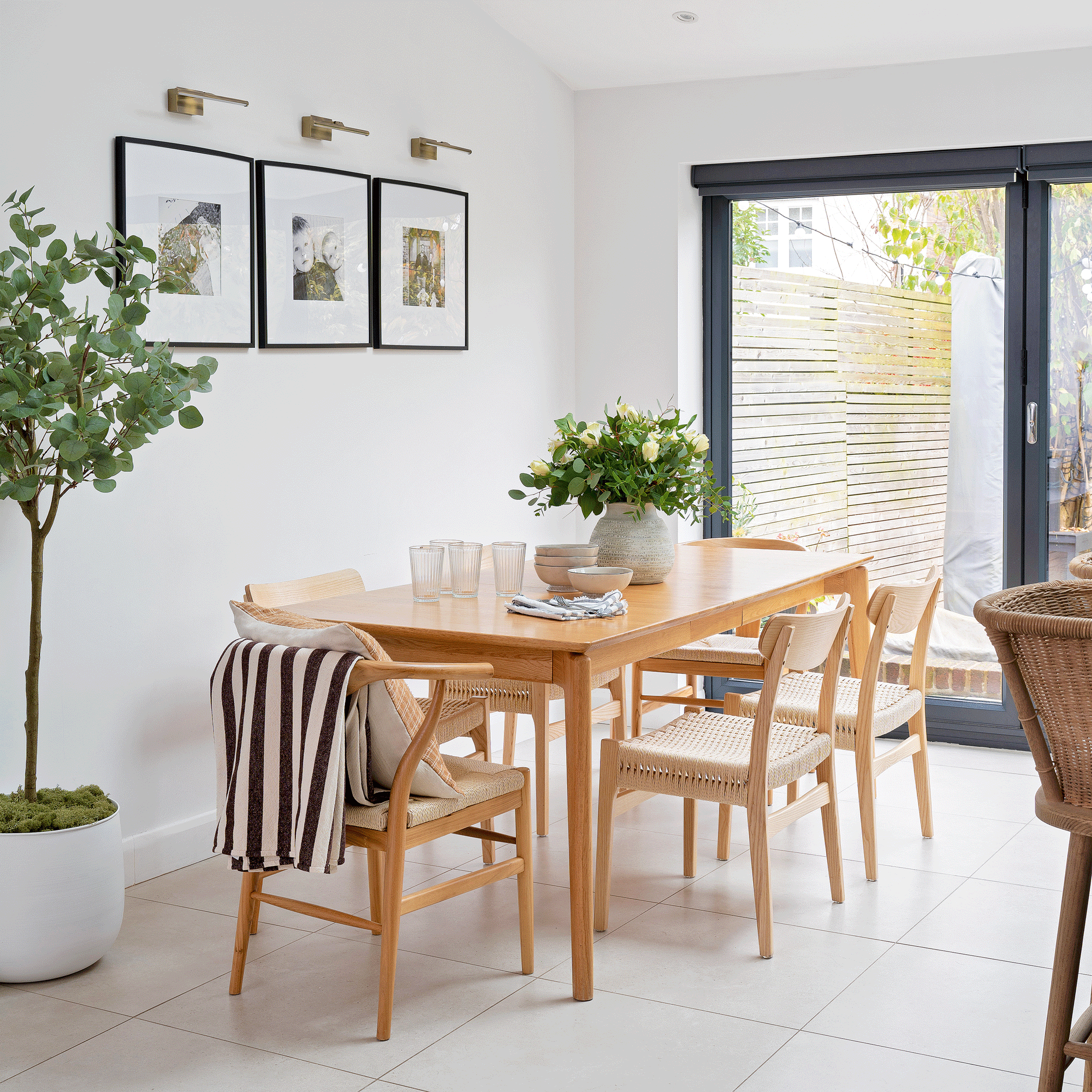 an open plan space with a dining area with a wooden dining table and chairs and patio doors that lead out into a garden