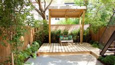 A sheltered deck area at the end of the garden with seating and string lights