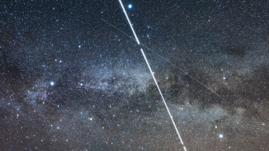 The International Space Station - the bright streak - shoots through the Milky Way between the stars of the Summer Triangle on May 29, 2017, during one of its several flybys that night. Other, fainter satellite trails are also visible. Vega is at the top, Deneb to the left, Altair to the right - the three stars of the Summer Triangle.