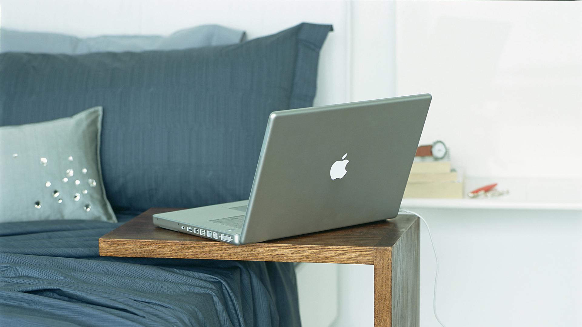 Bedroom with blue sheets on the bed and a portable side table with a laptop