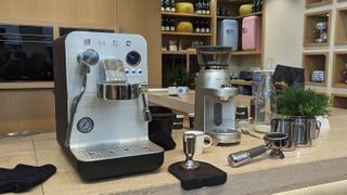 The EMC02 Mini Pro Espresso Coffee Machine on a countertop surrounded by coffee making accessories