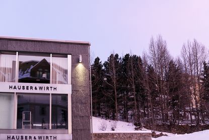 两层建筑的外部，从地板到天花板的玻璃窗在白天拍摄，地面上有雪，背景是树木