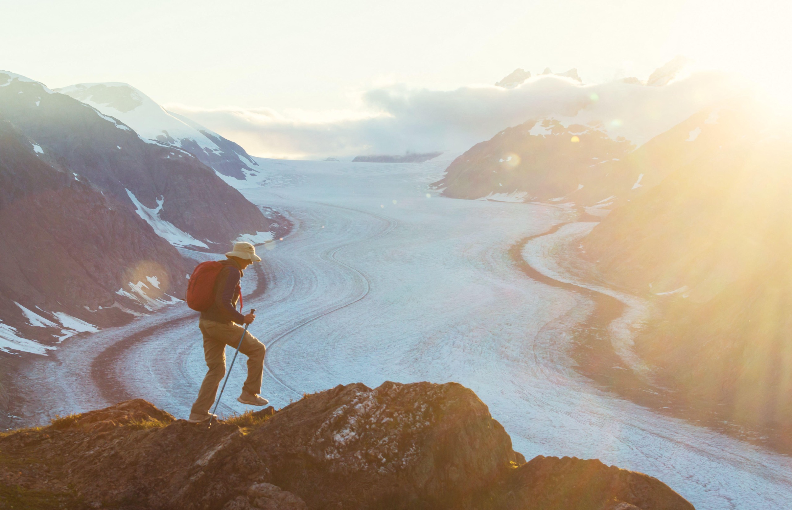 A man stands on top of a mountain overlooking a fjord in canada
