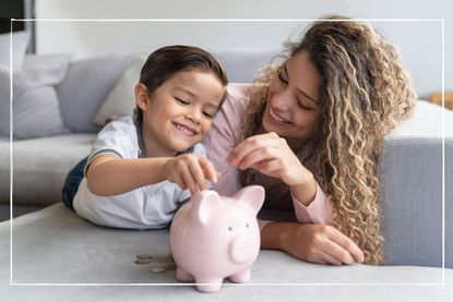 mother and son lying on sofa putting coins into a piggy bank