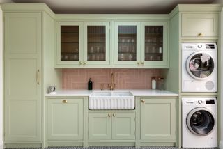 A pale green utility room with wall cabinets.