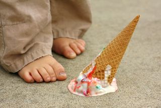 A child drops his ice cream cone on the ground.