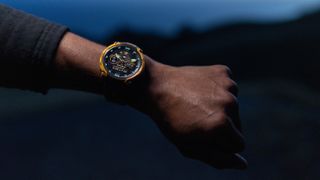 A photo of the Garmin Instinct Crossover AMOLED watch on a person's arm at night.