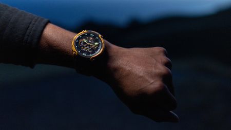 A photo of the Garmin Instinct Crossover AMOLED watch on a person's arm at night.