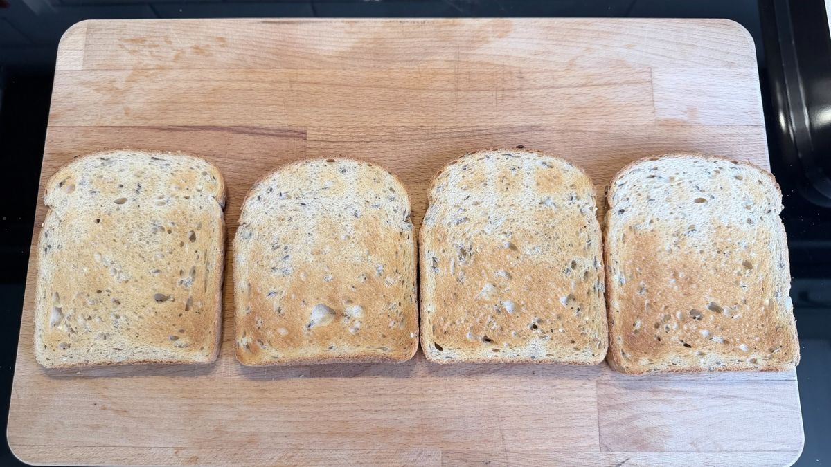 Four slices of toast on a wooden board after being cooked in the KitchenAid Pro Line toaster
