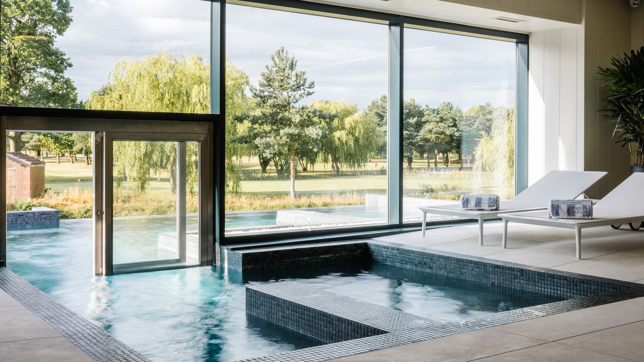 The indoor pool at Laceby Manor hotel with a large glass window looking out to the outdoor infinity pool