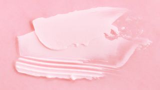 A smudge of lactic acid or glycolic acid skincare cream on a pink backdrop