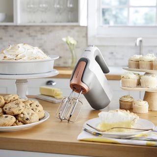 kitchen counter with hand mixer and cupcakes with cookies