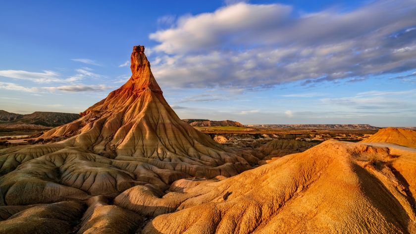 a tall rock structure bathed in golden light from the setting sun.