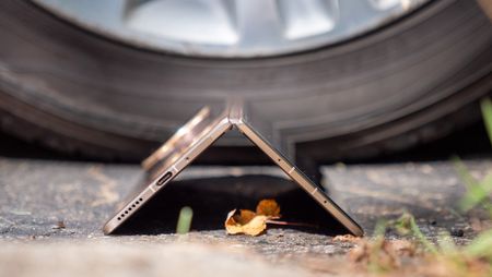 The gold Honor Magic V5 tented in front of a car tire