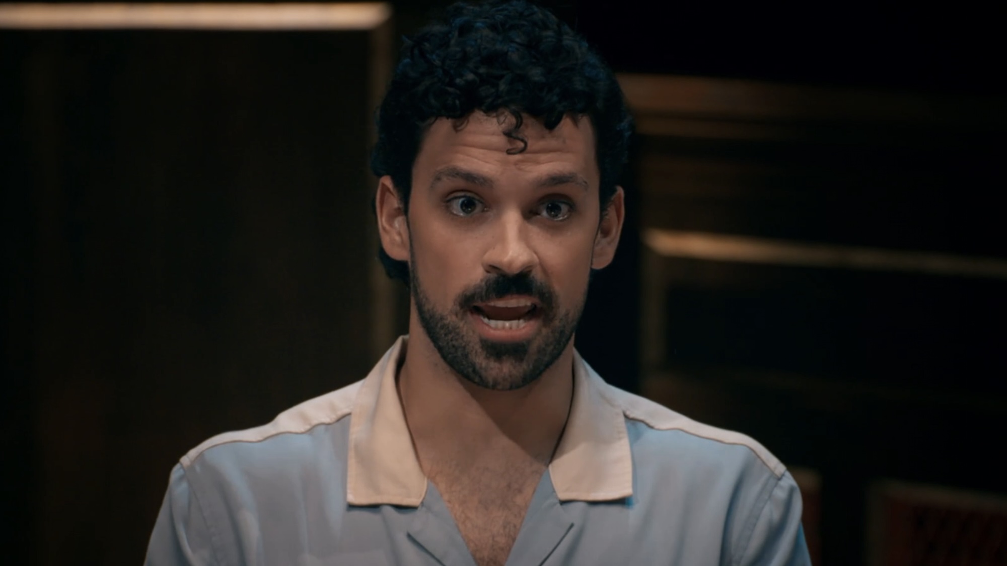 Victor wearing a polo shirt trying to convince his cast at the round table.  