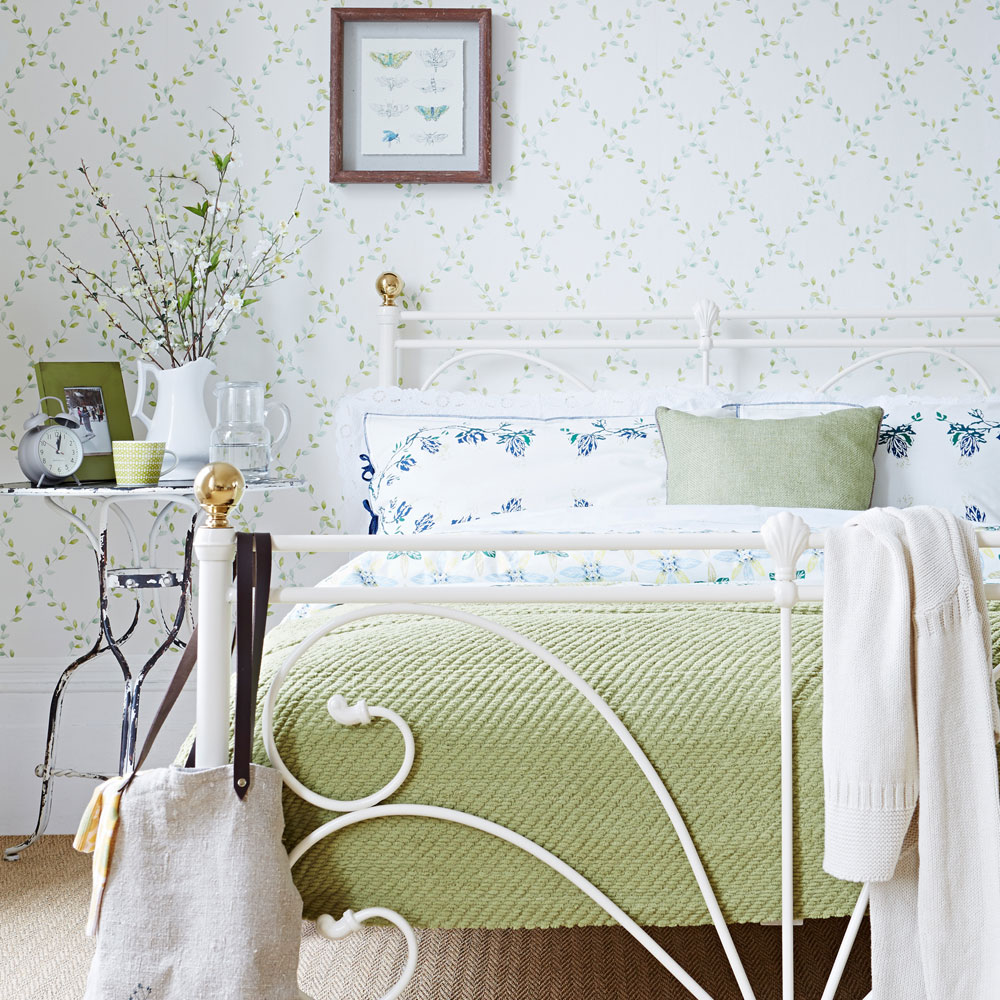 White bedroom with trellis wallpaper and wrought iron bed