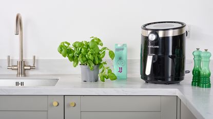 Lakeland Digital Crisp Air Fryer in modern grey kitchen with potted basil plant and plant based milk