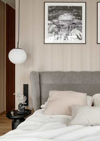 A bedroom with an upholstered gray headboard and comfortable looking sheets