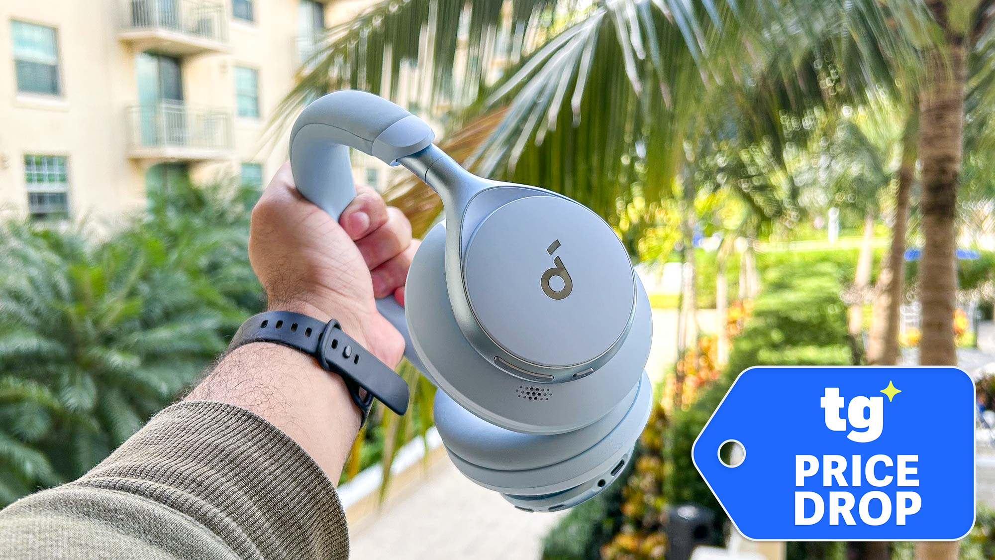 Soundcore Space One held in hand in front of palm tree