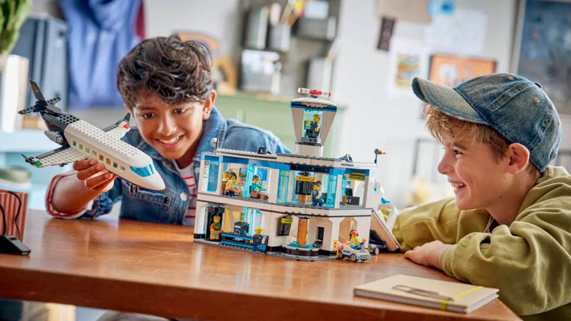 Two children play with the Lego Airport with Airplane set while seated at a wooden table