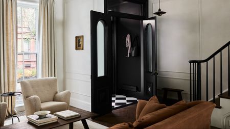 modern entryway with black door, brown velvet sofa, boucle armchair, timber coffee table