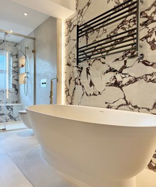 luxurious bathroom with white and red veined marble, freestanding bath, toilet and shower enclosure with seating area