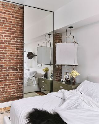 white bedroom with brick wall and big white lamp