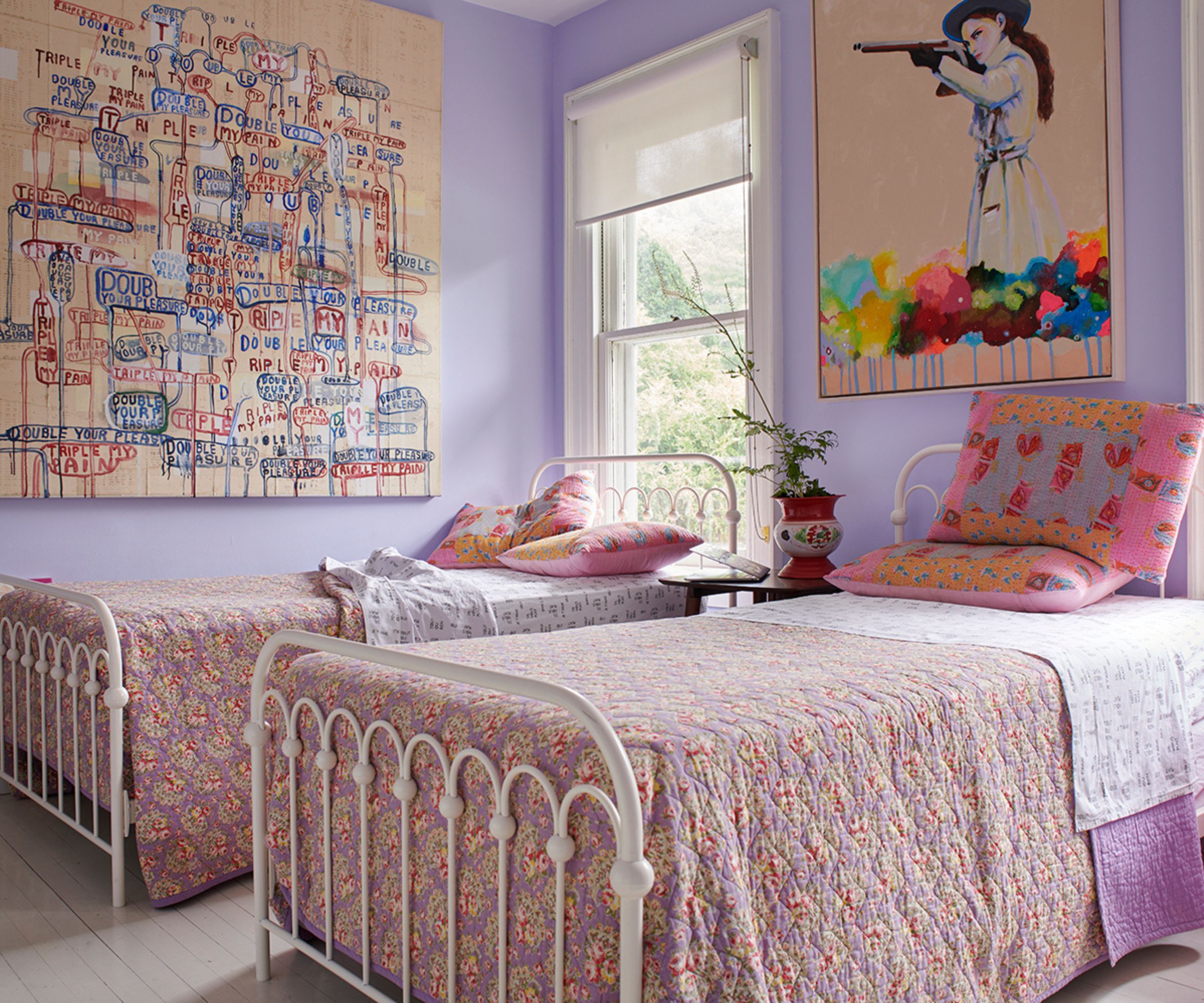 lilac kids bedroom with statement artwork and two twin white iron beds wit pink floral bedding