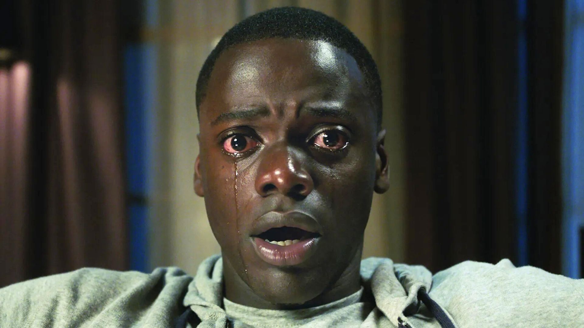 Daniel Kaluuya sits open-mouthed staring into the camera with tears running down his face