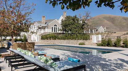 exterior of wood and stone house with swimming pool and striped chaises