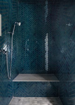 An example of blue bathroom ideas showing dark blue herringbone tiles in a shower space