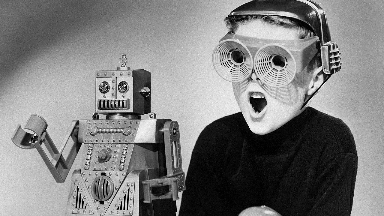 A black-and-white photo of a young boy playing with a toy robot