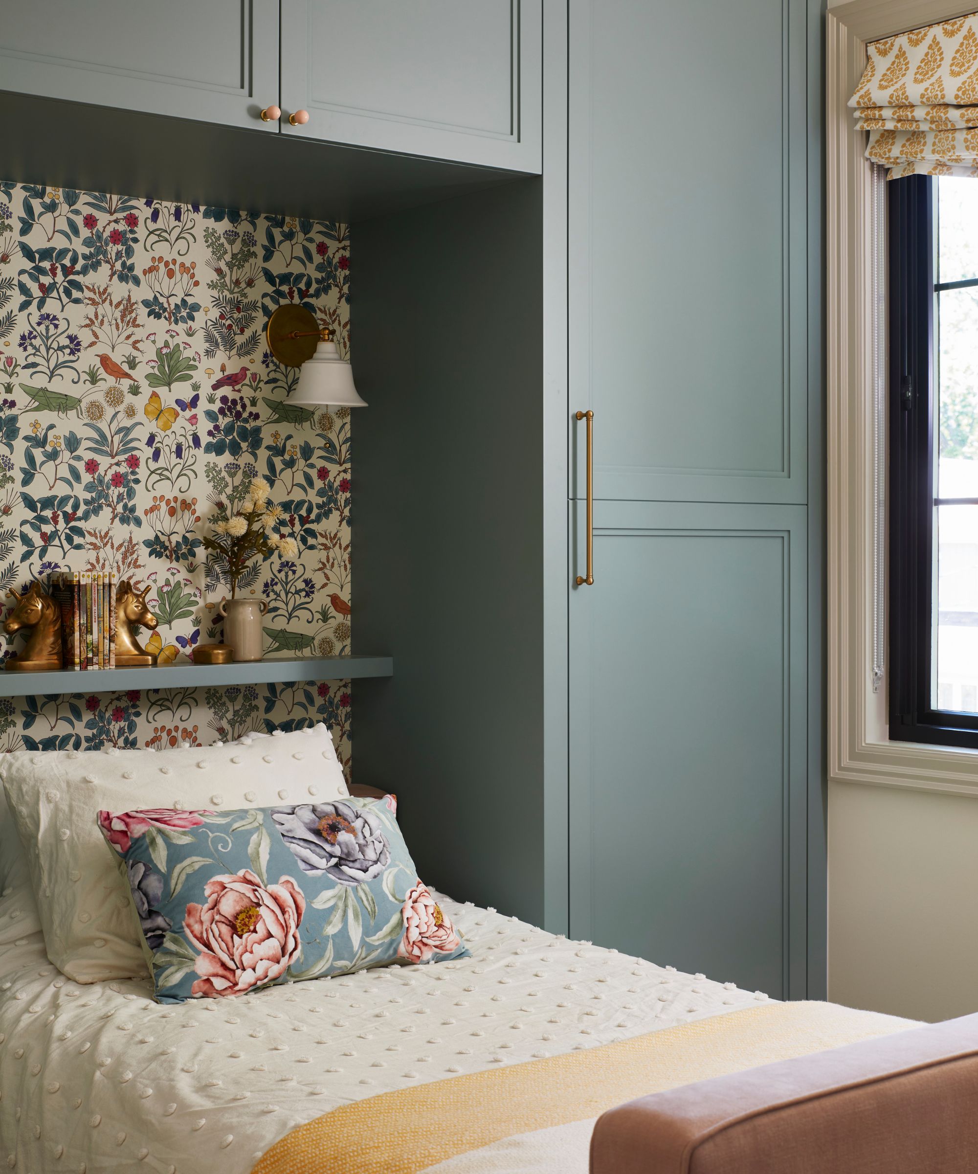 a little girls' bedroom with custom blue painted joinery, a single bed, and a butterfly and floral printed wallpaper