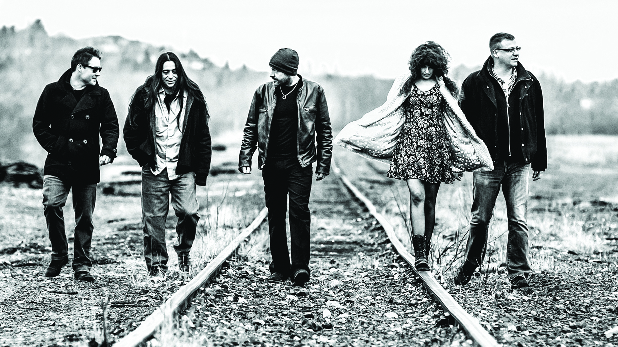 A black and white picture of Sulfur City walking along some railway tracks in the countryside.