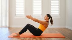 A woman performing the Pilates core exercise 'ab curl'