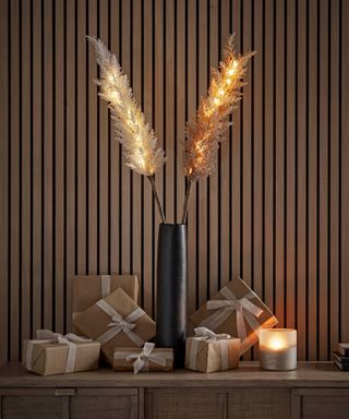 Two Lit Faux Pampas Grasses in a vase on a console table by cox and cox