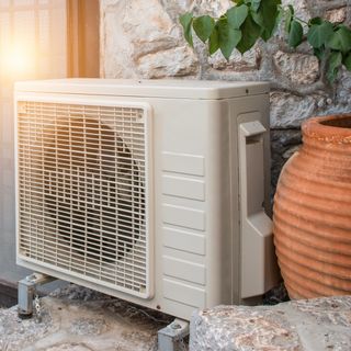 Air conditioner unit outdoors, next to large plant vase
