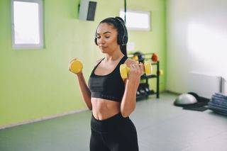 A woman trains with dumbbells in a studio space