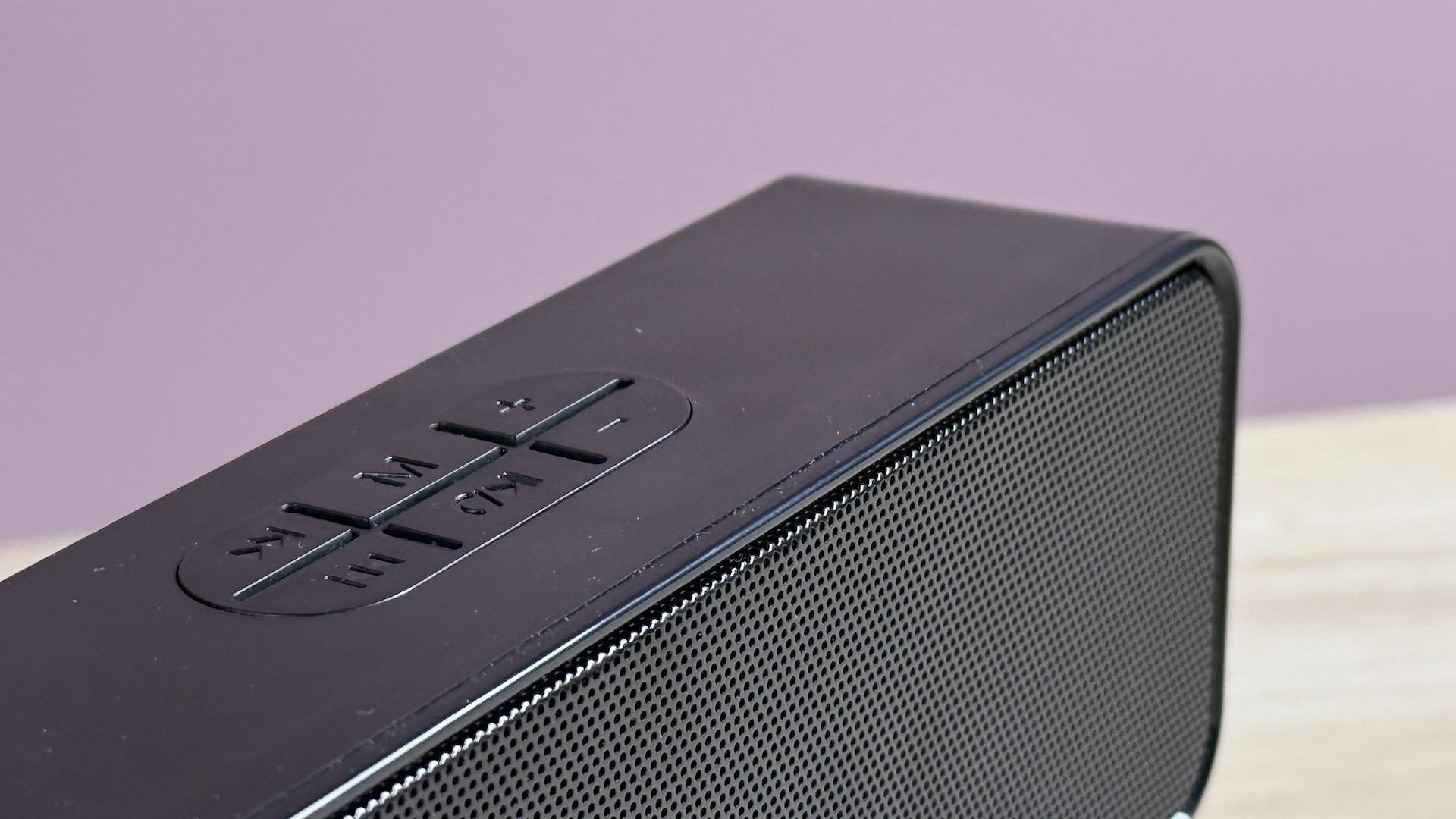 The corner of the WGO Bluetooth Speaker in front of a pink background.