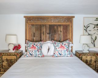 A bedroom at a Corfu villa with rustic wooden headboard and cushions in a blue and red Fanny Shorter print