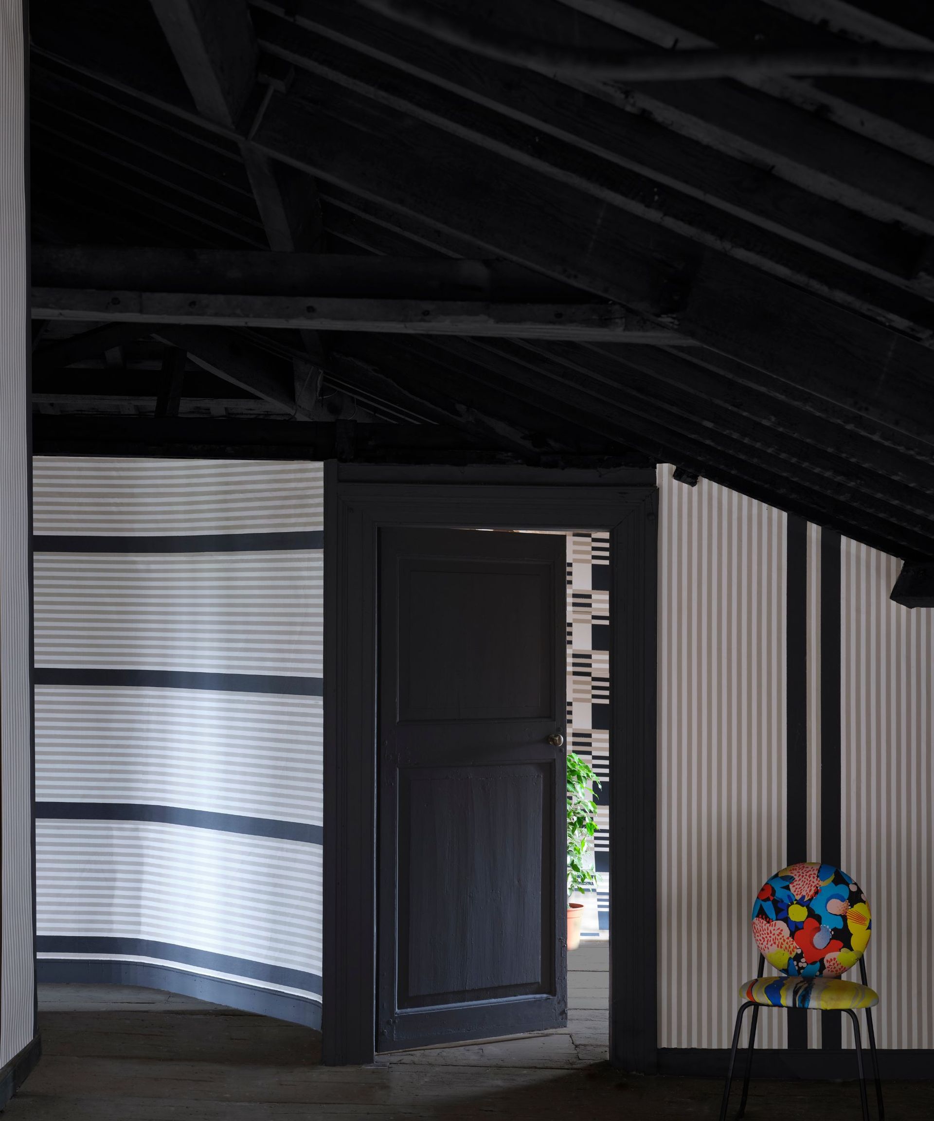 Black and white striped hallway with black door, ceiling and colorful chair