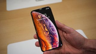 An iPhone XS in someone's hand, displaying the lock screen