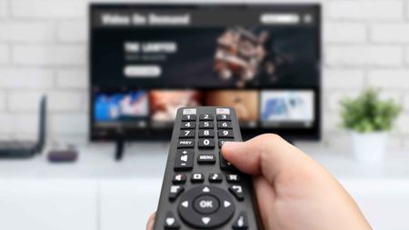 Man watching TV, remote control in hand. VOD service on TV