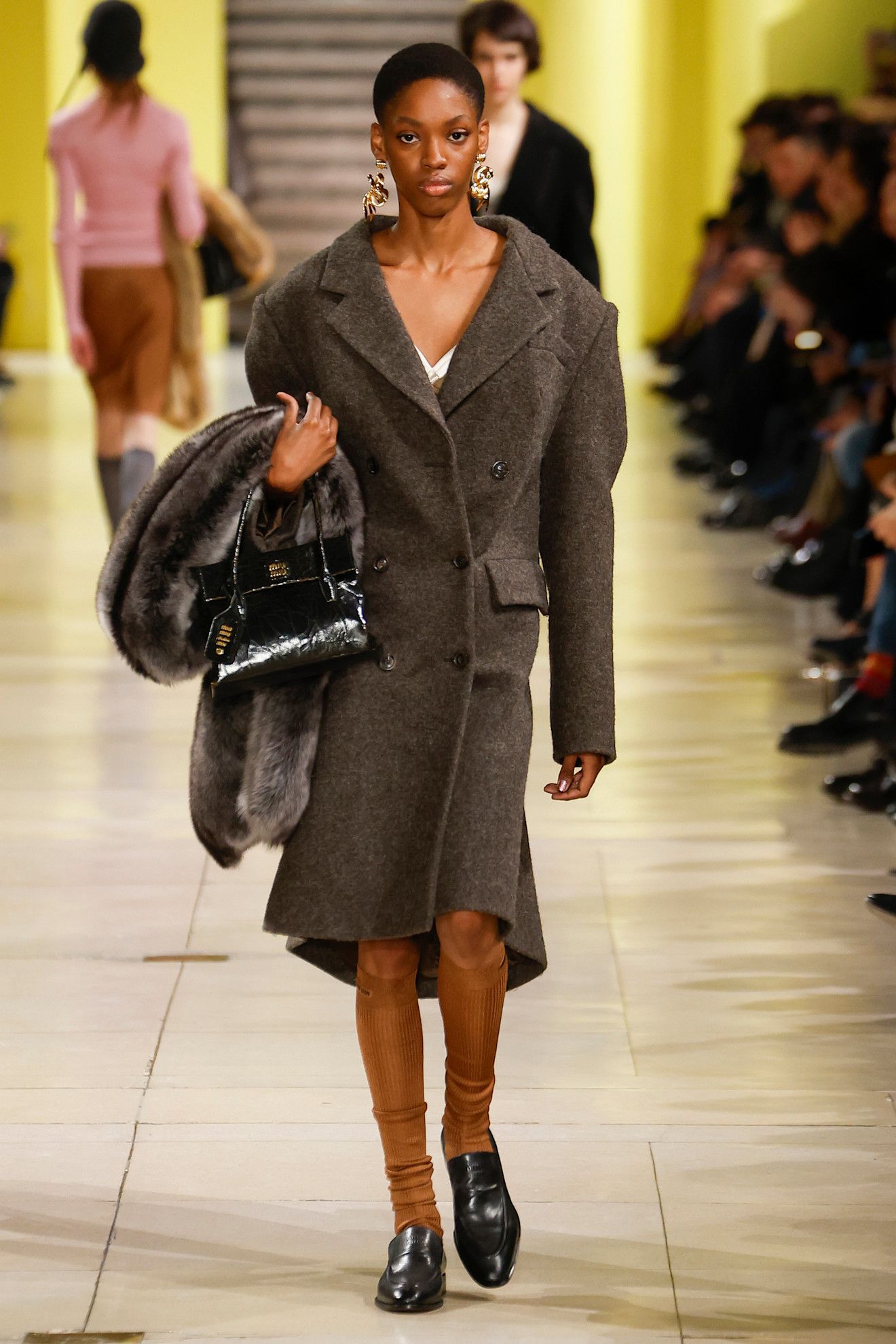 Miu Miu model carrying a patent black purse