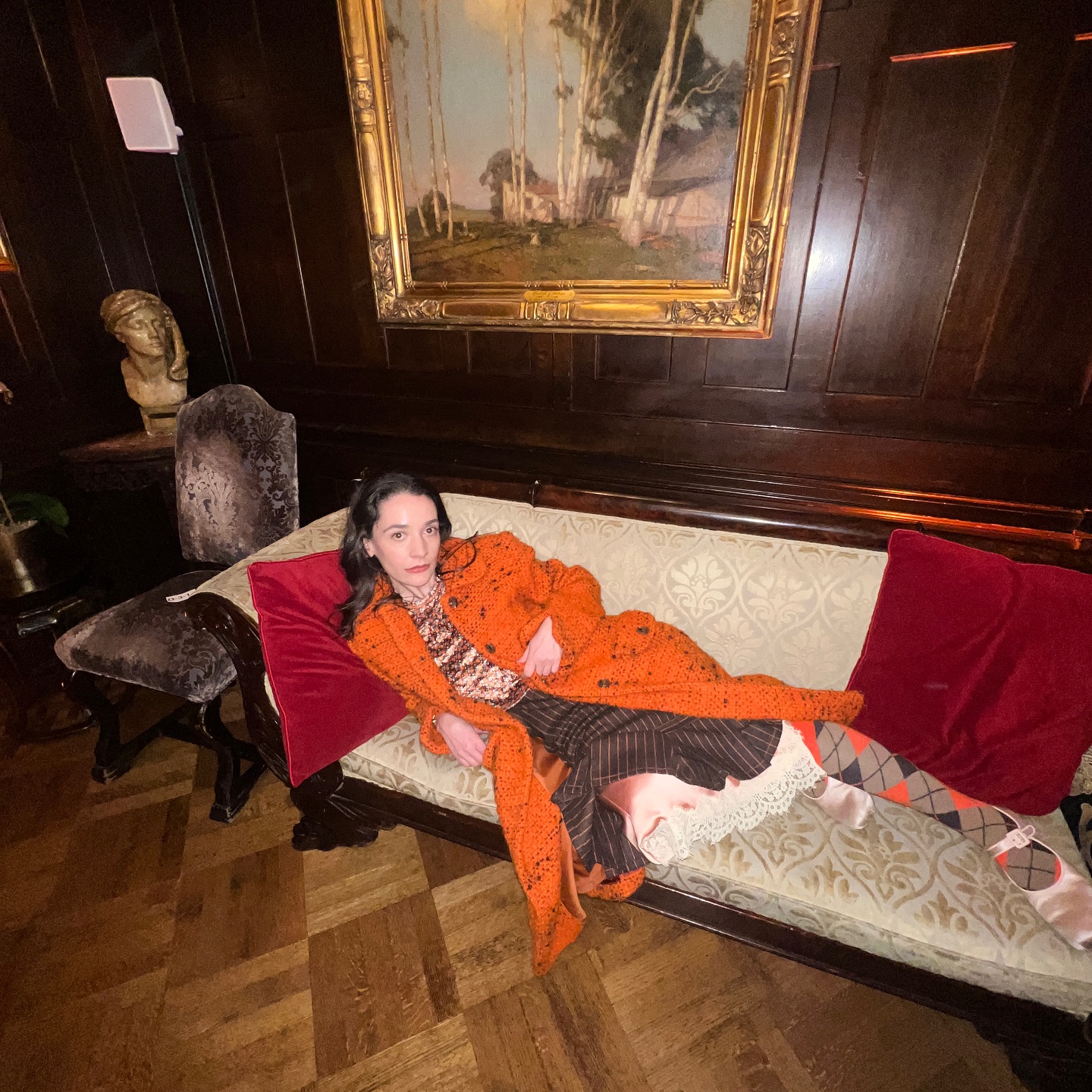 An image of @oldloserinbrooklyn wearing an orange coat with argyle tights.