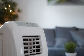 A close up of a dehumidifier with a living room sofa in the background